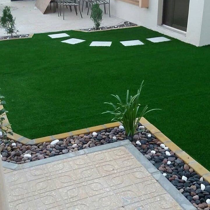 عشب صناعي مع حجارة ديكور وممر حجري في حديقة منزل بالمدينة المنورة